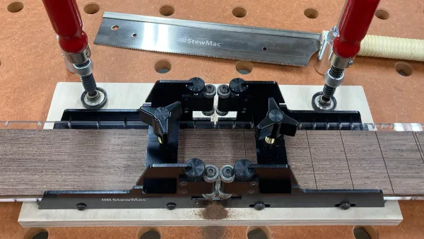 Image showing the Stewmac fret slotting miter box and Japanese fretting saw, with a partially cut fretboard.